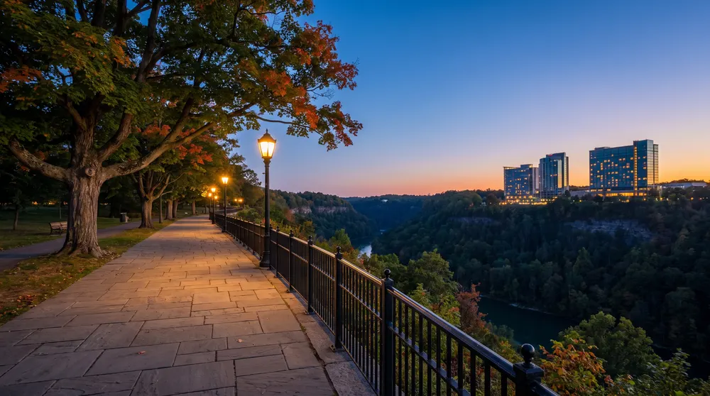 Lamp-lit promenade along a wooded gorge at dusk